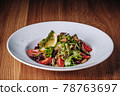 White Plate with Salad Stands on a Wooden Table in a Restaurant 78763697