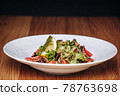 White Plate with Salad Stands on a Wooden Table in a Restaurant 78763698