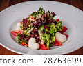 White Plate with Salad Stands on a Wooden Table in a Restaurant 78763699