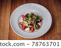 White Plate with Salad Stands on a Wooden Table in a Restaurant 78763701