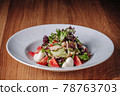 White Plate with Salad Stands on a Wooden Table in a Restaurant 78763703