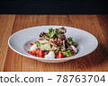 White Plate with Salad Stands on a Wooden Table in a Restaurant 78763704