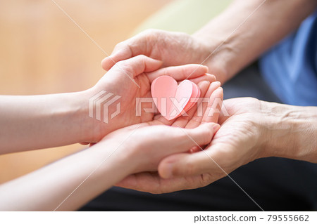 Hands of caregivers and elderly people with heart-shaped objects 79555662