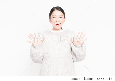 Woman standing in front of white background and making surprised gestures 88339218