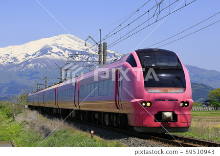 Limited express Inaho running with the remaining snow of Mt. Chokai in the background 89510943