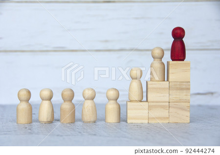 Wooden people figures on top of wooden blocks with red figure leading the rest. Business concept 92444274