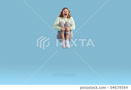 Happy funny crazy joyful excited young woman jumping on trampoline and screaming 94639564