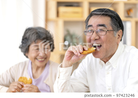 Senior couple eating rice crackers 97423246