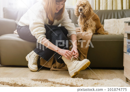 The girl ties her shoelaces before walking the dog. 101874775