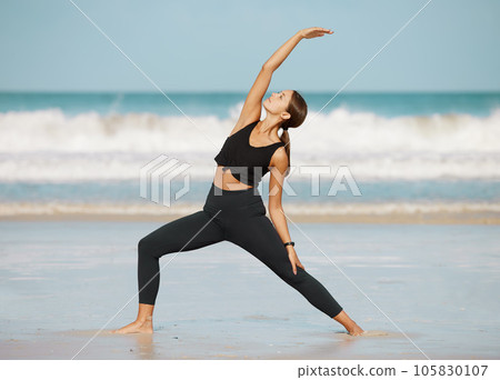 Stretch and strengthen your way to a better body. a young woman doing a crescent lunge while practising yoga at the beach. 105830107