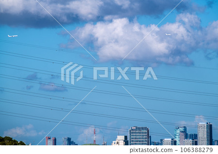 Tokyo cityscape in Japan Two planes and an aircraft over Shibuya. Air travel demand recovery…Shibuya Scramble Square in the back right = August 106388279