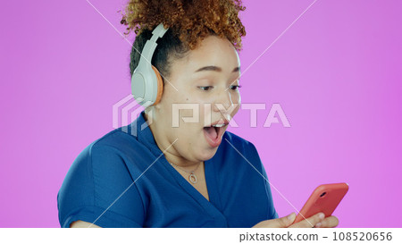 Woman, phone and wow with headphones for winner, promotion or announcement in studio on purple background. Smartphone, person and surprised for notification, sale and lottery news with mock up space 108520656