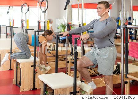 Man does gymnastics in gym and performs bends and stretches on wunda chair 109413809