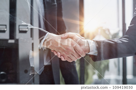 executives shaking hands in front of their manager and a colleague 109419030