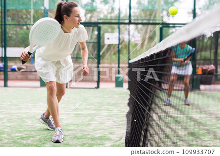 Young sporty woman playing paddle tennis outdoors 109933707