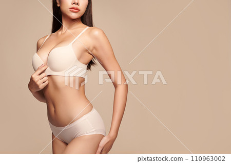 Confident beautiful young asian woman posing in white lingerie on beige background, Perfect body, 110963002