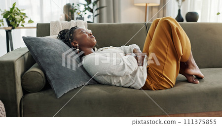 Home, pain and black woman on a couch, cramps and stomach with sickness, suffering and disease in the living room. African person, apartment and girl with abdominal problem, tummy ache and period 111375855