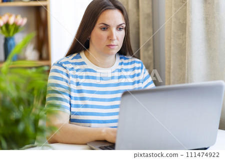 Focused Woman Working on Laptop in a Home Setting 111474922