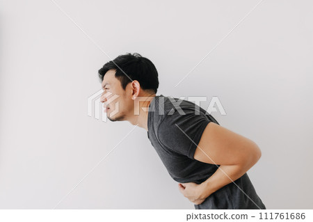 Asian man in black t-shirt feeling sick and stomach ache isolated on white. 111761686