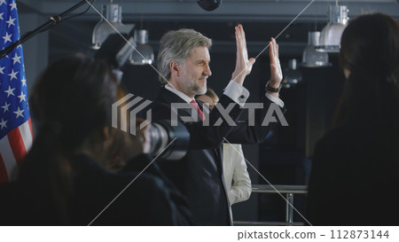 President of the USA waves his hand and poses for media cameras 112873144