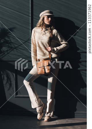 Studio portrait of beautiful woman with a curly blond hair holding black bag, posing on gray background. 113371962