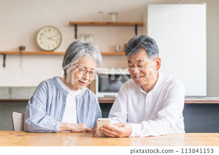 Asian elderly couple using smartphones/smartphone apps (smile/fun) 113841153