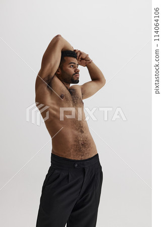 Handsome young African-American man posing shirtless in black pants isolated on white background. Muscular healthy body shape 114064106