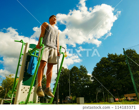 Man flexing arms in outdoor gym 114183371