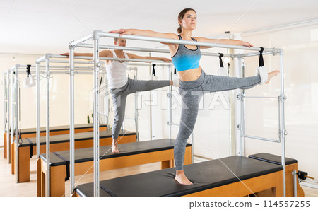 Woman working out on the trapeze table in fitness gym. Pilates and healthy lifestyle concept 114557255