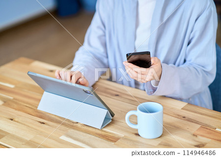 A woman operating a tablet PC and a smartphone 114946486