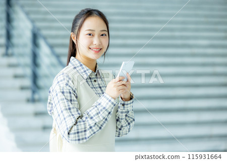 A young woman operating a smartphone at school 115931664