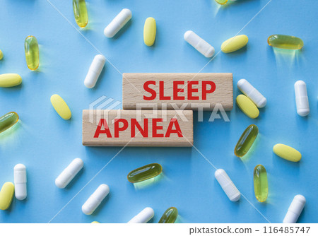 Sleep Apnea symbol. Concept word Sleep Apnea on wooden blocks. Beautiful blue background with pills. Medicine and Sleep Apnea concept. Copy space 116485747