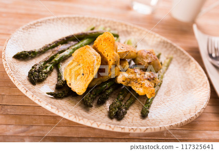 Cooked dish. Chicken nuggets with green asparagus on plate 117325641