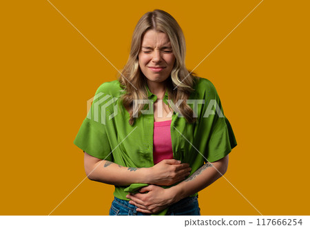 Young woman squeezing belly with hands. abdominal pain, suffering stomach ache 117666254