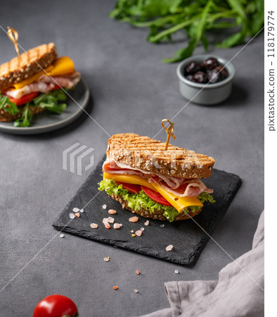 Club sandwich on a board with a  bacon, cheese, tomato and lettuce on a dark background 118179774