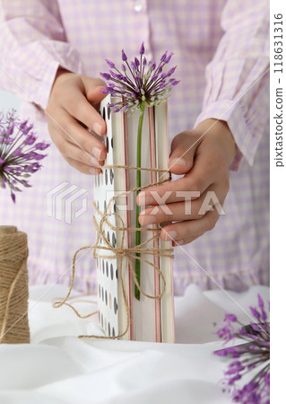 Books with flowers wrapped in burlap thread on a light background. 118631316