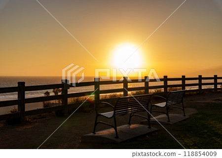 A sunset over the ocean with two benches for relaxation Santa Monica 118854009