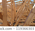 View through wooden trusses under construction, showcasing the symmetrical alignment and complex framework against the sky 119366303