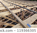 Overhead view of wooden trusses and beams in a large-scale construction project, featuring metal connector plates for structural integrity 119366305