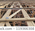 Aerial view of interconnected wooden beams and trusses forming the framework of a large building under construction 119366308