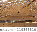 Interior view of interconnected trusses forming a robust wooden frame, capturing the depth and intricate arrangement of the construction 119366310