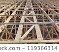 Top view of extensive wooden roof trusses with metal connectors, illustrating the structural complexity and layout of a construction site 119366314