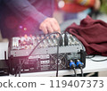 Sound Mixer with Cables and Person Adjusting Controls at Outdoor Event 119407373