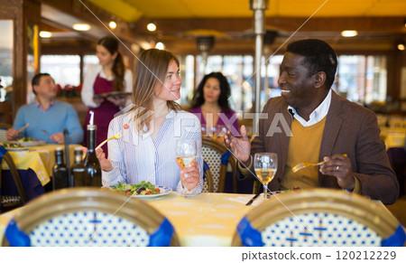 Husband and wife eating and talking in restaurant 120212229