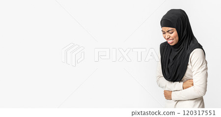 Sick black muslim girl in hijab suffering from acute abdominal pain, touching her belly, standing over grey studio background with free space 120317551