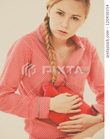 Woman feeling stomach cramps lying on bed 120430354