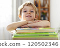 Smiling child resting on book stack 120502346