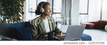 A woman in headphones sits in front of a laptop computer 120555500