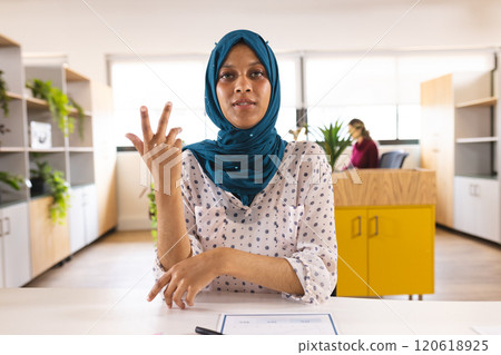 Portrait of happy biracial casual businesswoman with hijab having video call in creative office 120618925