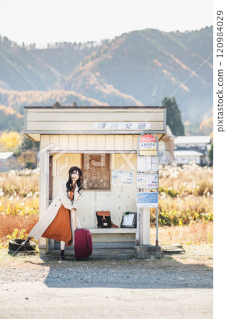 A young woman waiting for a bus at a bus stop. Photo courtesy of Ugo Kotsu. 120984029